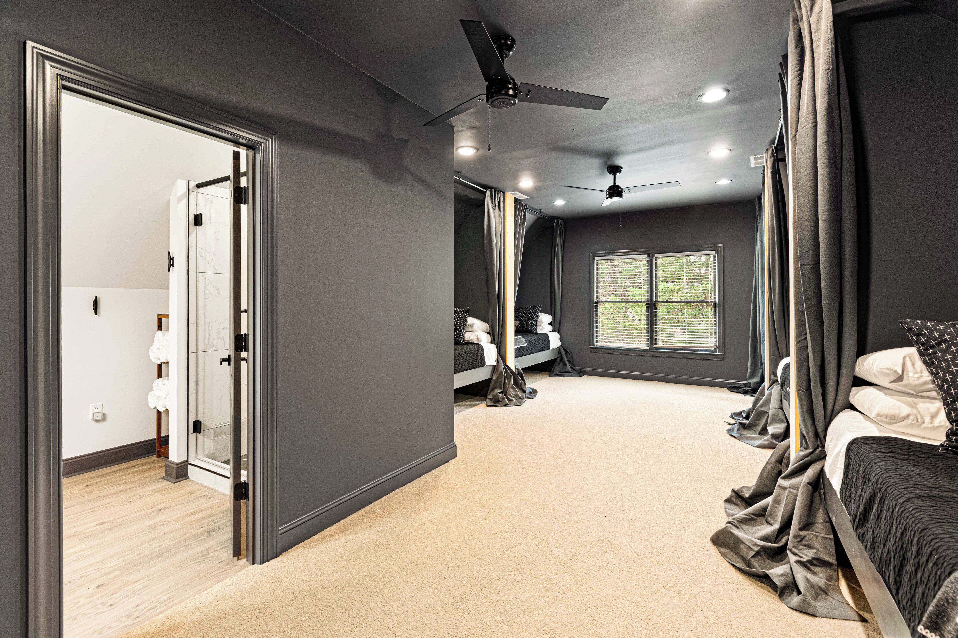 A bedroom with a bed, a ceiling fan, a window, and a door leading to another room.