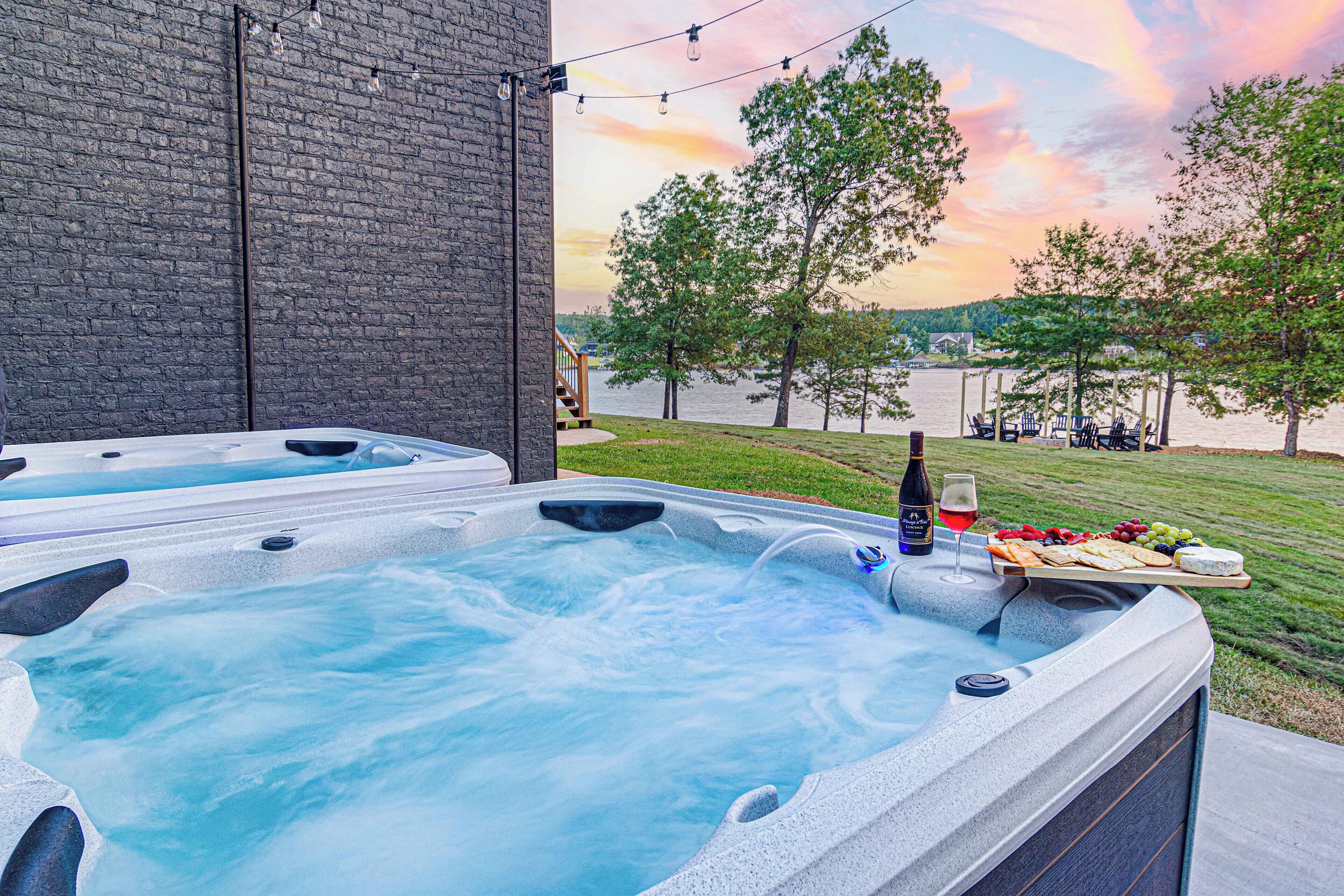 A hot tub with a wooden deck and a table with snacks and drinks.