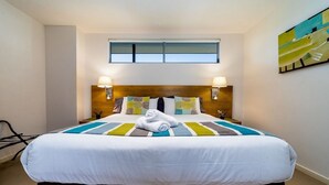 Ein Hotelzimmer mit einem großen Bett, zwei Nachttischlampen, einem Fenster und einem Gemälde an der Wand.