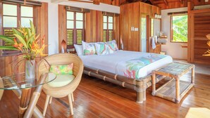 Una habitación de madera con una cama, una mesa de vidrio y una silla.