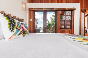 Un dormitorio con una cama grande, vistas a un balcón exterior a través de un ventanal corredero, y una pared de madera.