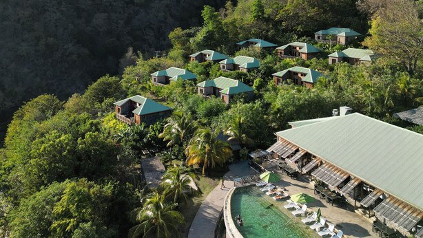 Un resort con varias edificaciones, piscina y abundante vegetación.