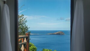 Una habitación con vista al mar, una terraza de madera y una cortina blanca.