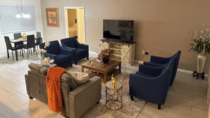 Una sala de estar con sofá, sillones, mesa de centro y televisor.