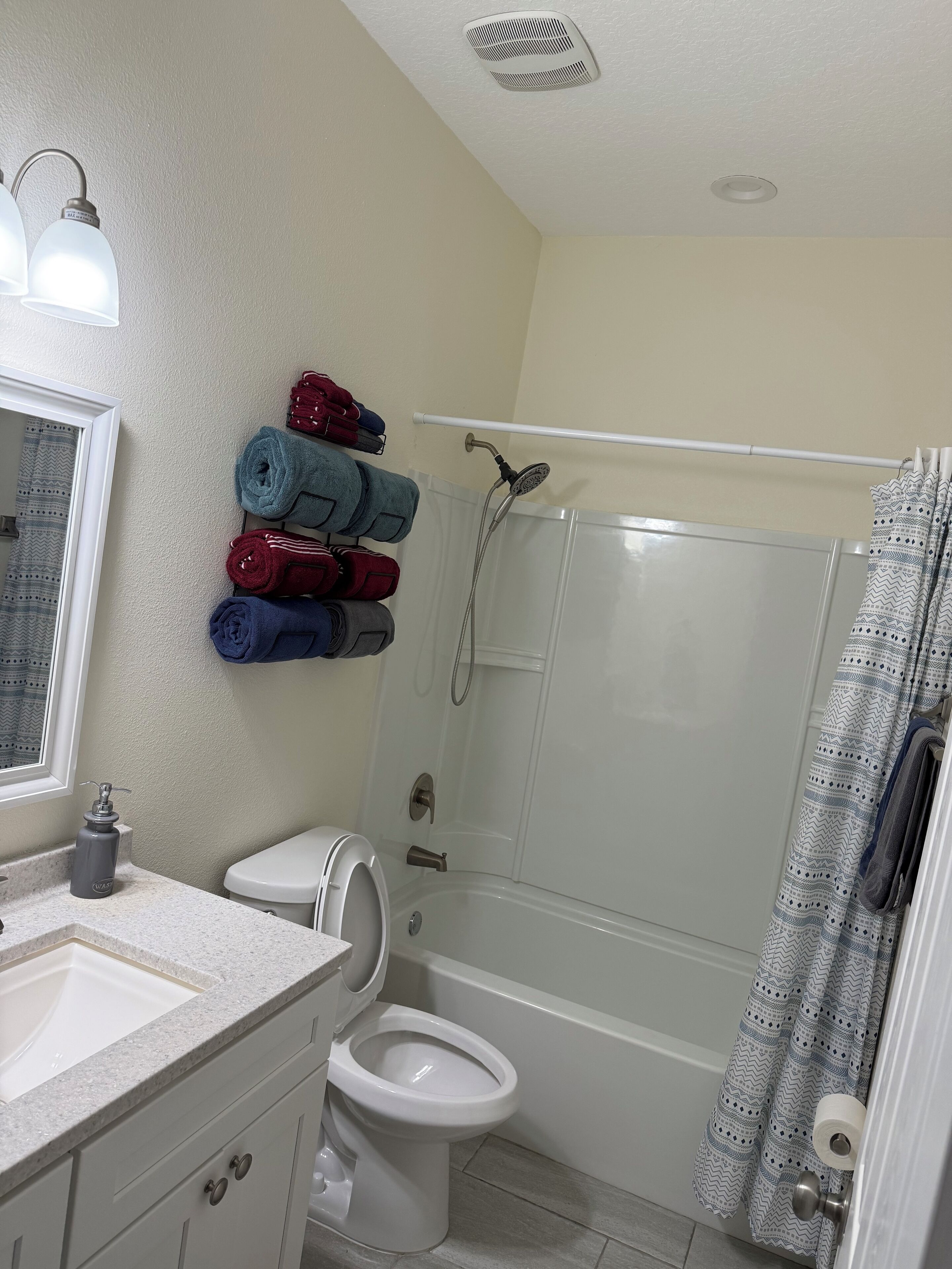 A bathroom with a toilet, sink, shower, and towel rack.