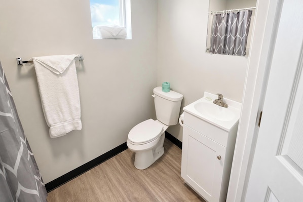A bathroom with a toilet, sink, and towel rack. - Rocky Mount Motel near Hwy 220 (Rocky Mount)