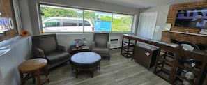 A room with a large window, a TV, a fireplace, and a small table. - Rocky Mount Motel near Hwy 220 (Rocky Mount)