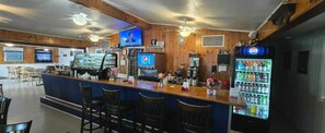 A bar area with a counter, seating, a Pepsi refrigerator, and a television screen. - Rocky Mount Motel near Hwy 220 (Rocky Mount)