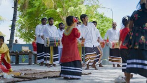 A group of people in traditional attire, some playing drums, in an outdoor setting with trees and a clear sky. - Nest by Hawks Hotels Kamadhoo Baa Atoll (Kamadhoo)