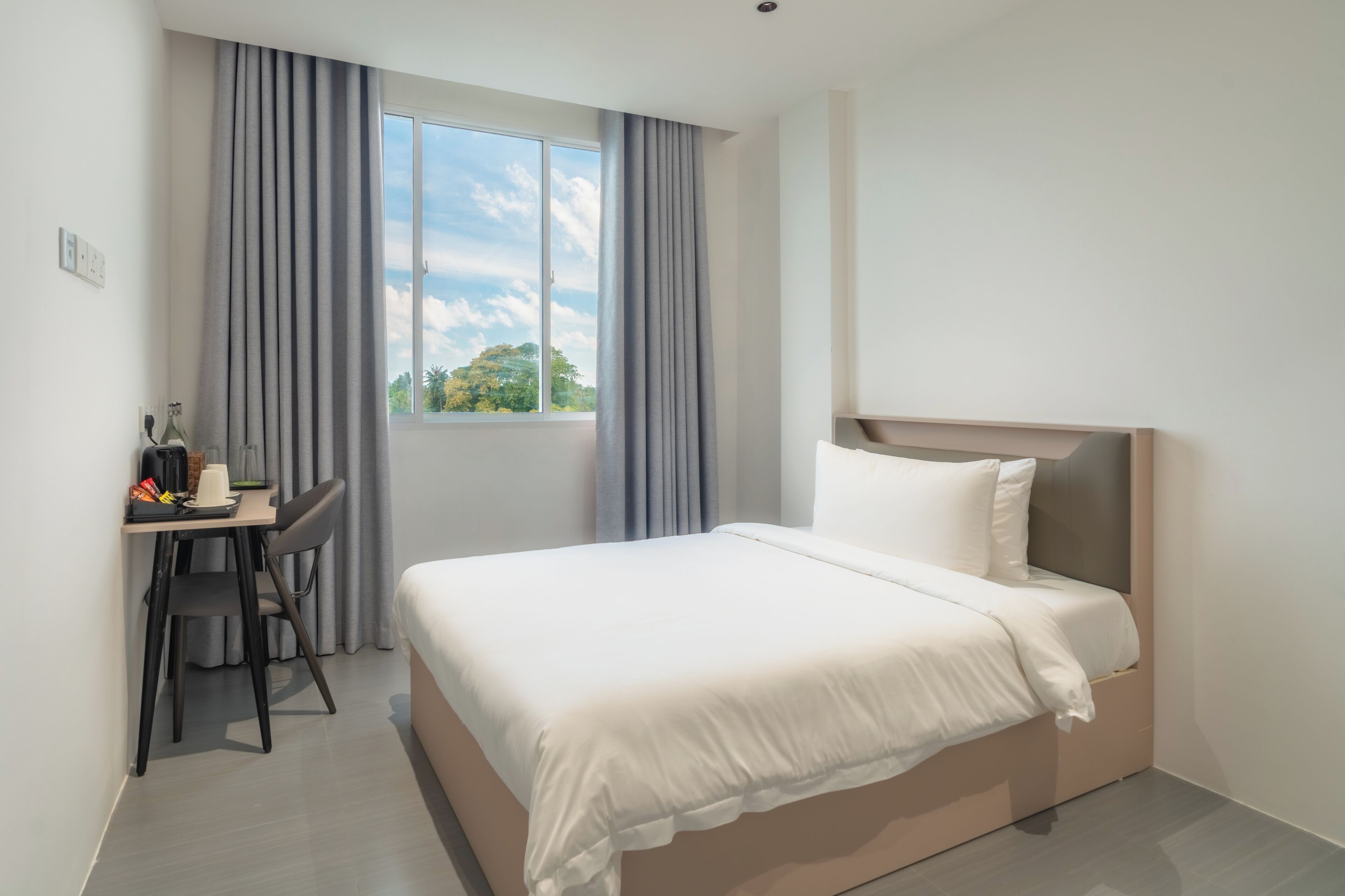 Een hotelkamer met een bed, een bureau en een raam met gordijnen.