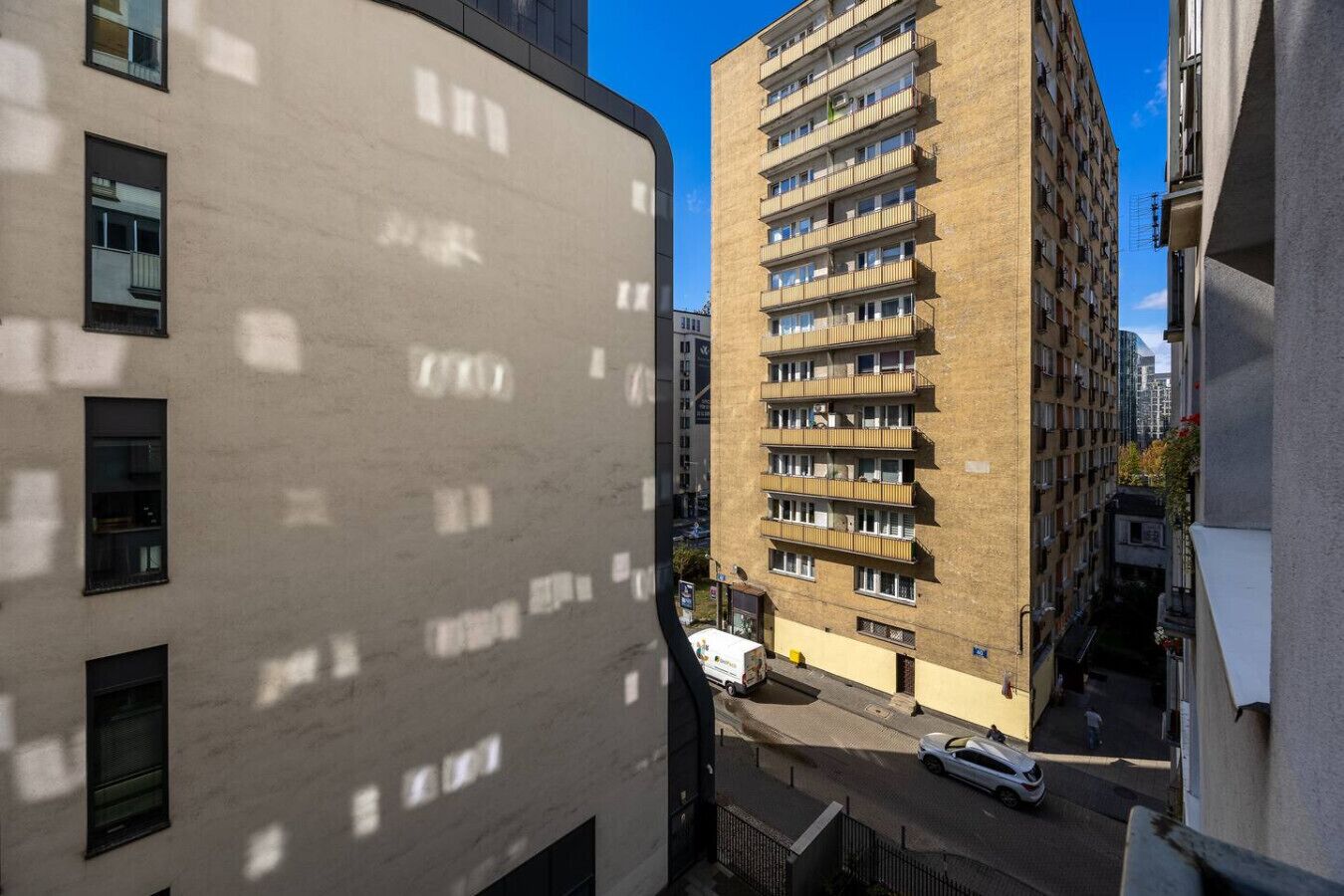 Un immeuble à plusieurs étages, doté de balcons, donnant sur une rue étroite.