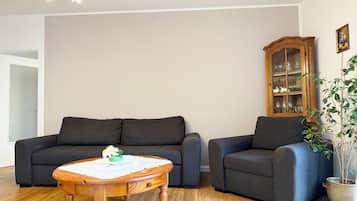A living room with a wooden coffee table, two dark sofas, a wooden cabinet, and a potted plant.