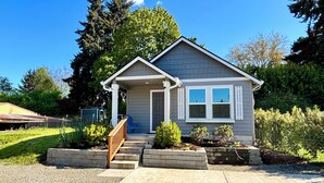 Une maison de plain-pied avec un porche à l’avant, un petit jardin devant et une allée en gravier.
