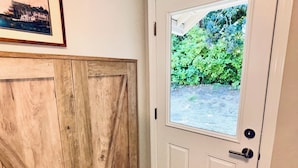 Une porte avec une fenêtre, un meuble en bois et un tapis à motifs.