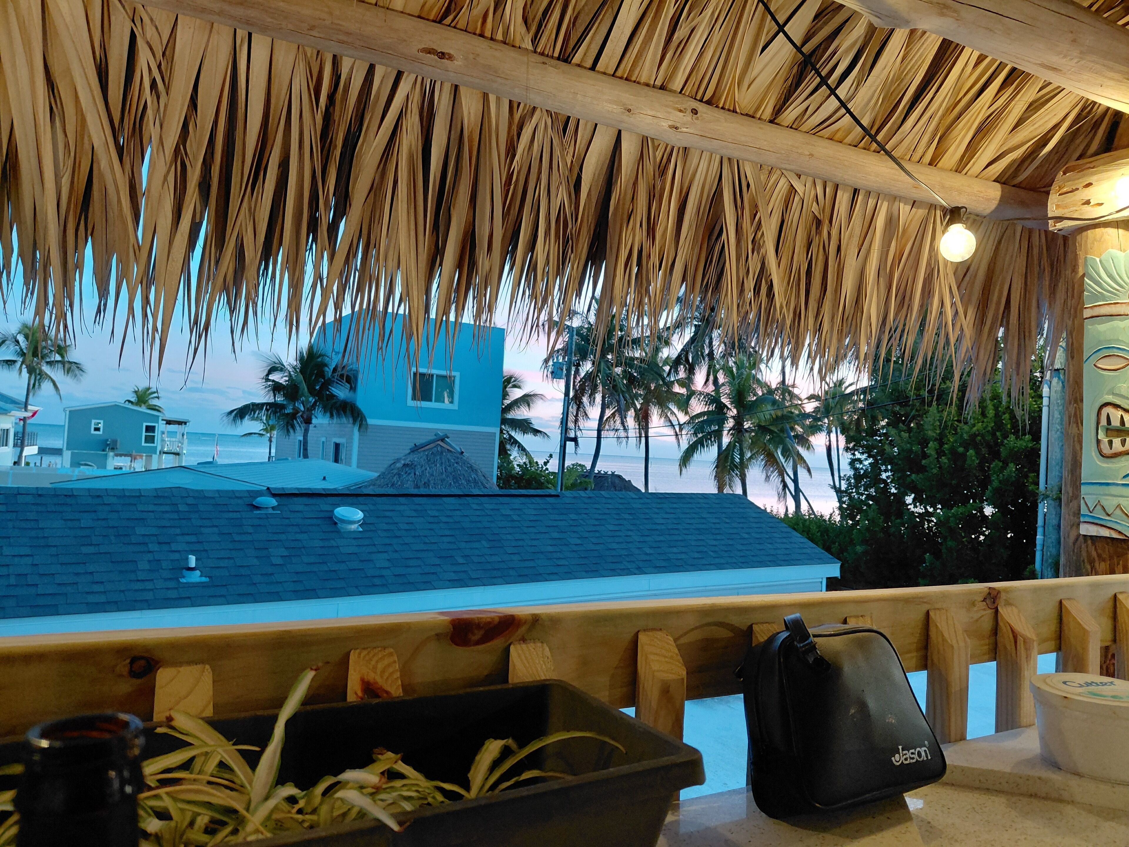 Ein Restaurant direkt am Strand mit einem Reetdach, Blick auf das Meer und einer Holzterrasse.