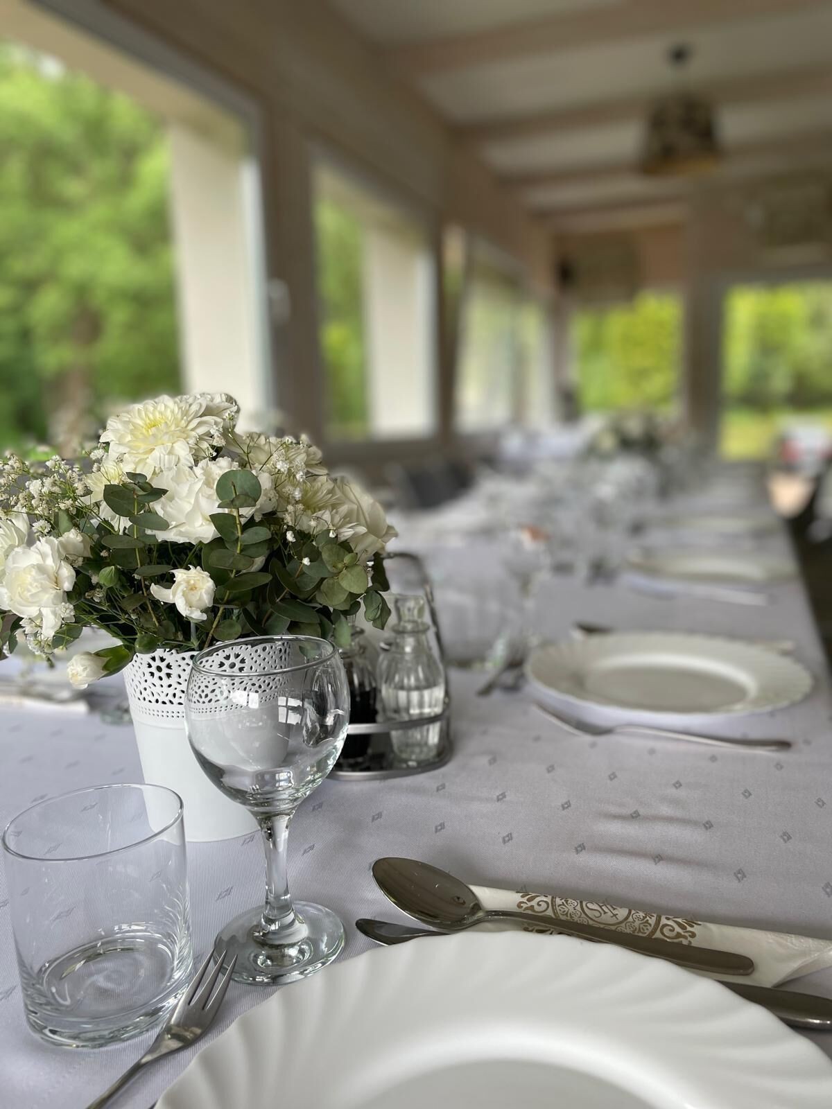 Une table mise pour un repas, avec des assiettes blanches, des couverts en argent et un verre d’eau.