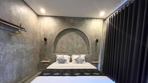 Een moderne slaapkamer met een groot bed, een houten plank en een donker gordijn.