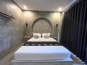 Une chambre moderne avec un grand lit, une étagère en bois et un rideau foncé.