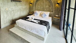 Een moderne slaapkamer met een groot bed, een ventilator en uitzicht door een glazen deur.