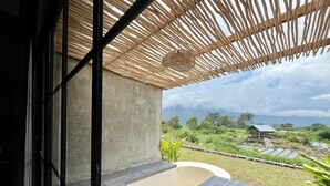 A modern outdoor space with a concrete wall, a wooden pergola, and a view of a lush landscape. - Batur Sunsun Kintamani By Zuzu (Kintamani)
