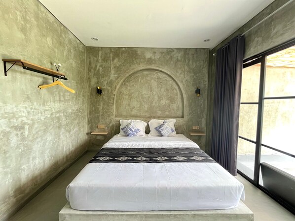 A bedroom with a large bed, a wooden shelf, and a window with curtains.