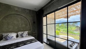 A bedroom with a large window, a bed with white bedding, and a view of greenery outside. - Batur Sunsun Kintamani By Zuzu (Kintamani)