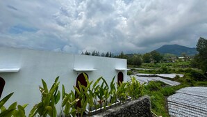 A building with a flat roof, a red door, and a view of terraced fields and mountains in the background. - Batur Sunsun Kintamani By Zuzu (Kintamani)