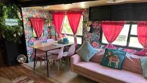 Un intérieur chaleureux avec un coin repas, un canapé agrémenté de coussins et un tapis aux couleurs vives.
