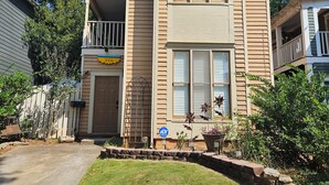 A two-story house with a front porch, a garage, and a small front yard with a lawn and a stone border. - Charming Historic Grant Park Home / Atlanta Gem! (Atlanta)