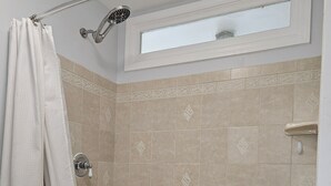 A bathroom with a bathtub, shower, and a window above the tub. - Charming Historic Grant Park Home / Atlanta Gem! (Atlanta)