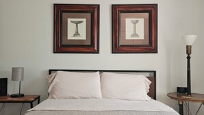 A neatly made bed with folded towels, a bedside lamp, and two framed pictures on the wall. - Charming Historic Grant Park Home / Atlanta Gem! (Atlanta)