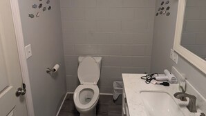 A small, compact bathroom with a toilet, sink, and mirror.
