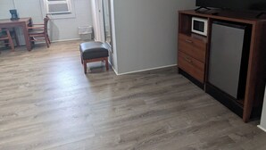 A spacious living area with a flat-screen TV, wooden furniture, and a small kitchenette.