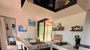 Cocina compacta con una isla central, zona de comedor con una guitarra y vistas a zonas verdes.