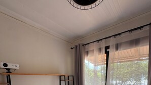 Un dormitorio con cama, ventilador de techo, proyector y ventana con cortinas.