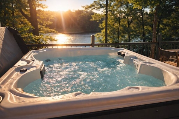 A hot tub with a view of a lake and trees during sunset.