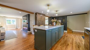 A spacious kitchen with wooden flooring, a central island, and dark cabinetry. - Newly Built|Riverfront|Kayaks|Hot tub|King|AC (Alpena)