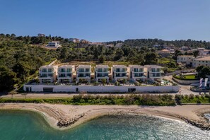 Un hotel moderno con varios edificios blancos, una playa de arena y un mar azul cristalino.