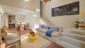 A modern living room with a sofa, chairs, a coffee table, and a staircase.