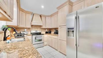A kitchen with light wood cabinets, a granite countertop, stainless steel appliances, and a built-in oven.