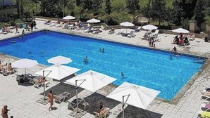 A swimming pool with sun loungers and umbrellas, surrounded by greenery and buildings. - Nonstop electricity 1 bedroom beachfront apartment & Seaview Family Duplex (Jabal Lubnan)