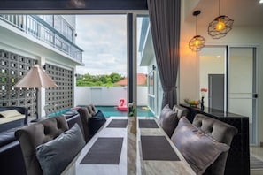 A modern living room with a pool, outdoor seating, and a balcony. - La Lune Pool Villa Chiang Mai (Saraphi)