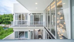 Un bâtiment moderne à deux étages, doté de grandes fenêtres en verre, d’un balcon et d’un escalier menant à l’étage supérieur.