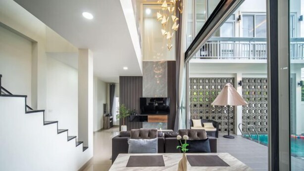 Un salon moderne comprenant un ensemble de canapés, une table à manger avec des sets de table et un vase décoratif.