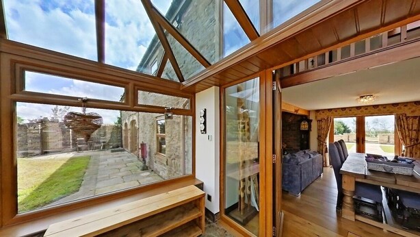 Quarto com um amplo claraboia, bancos de madeira e vista para um jardim e muro de pedra.