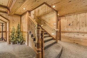 A wooden interior with a staircase, carpeted steps, and a Christmas tree.