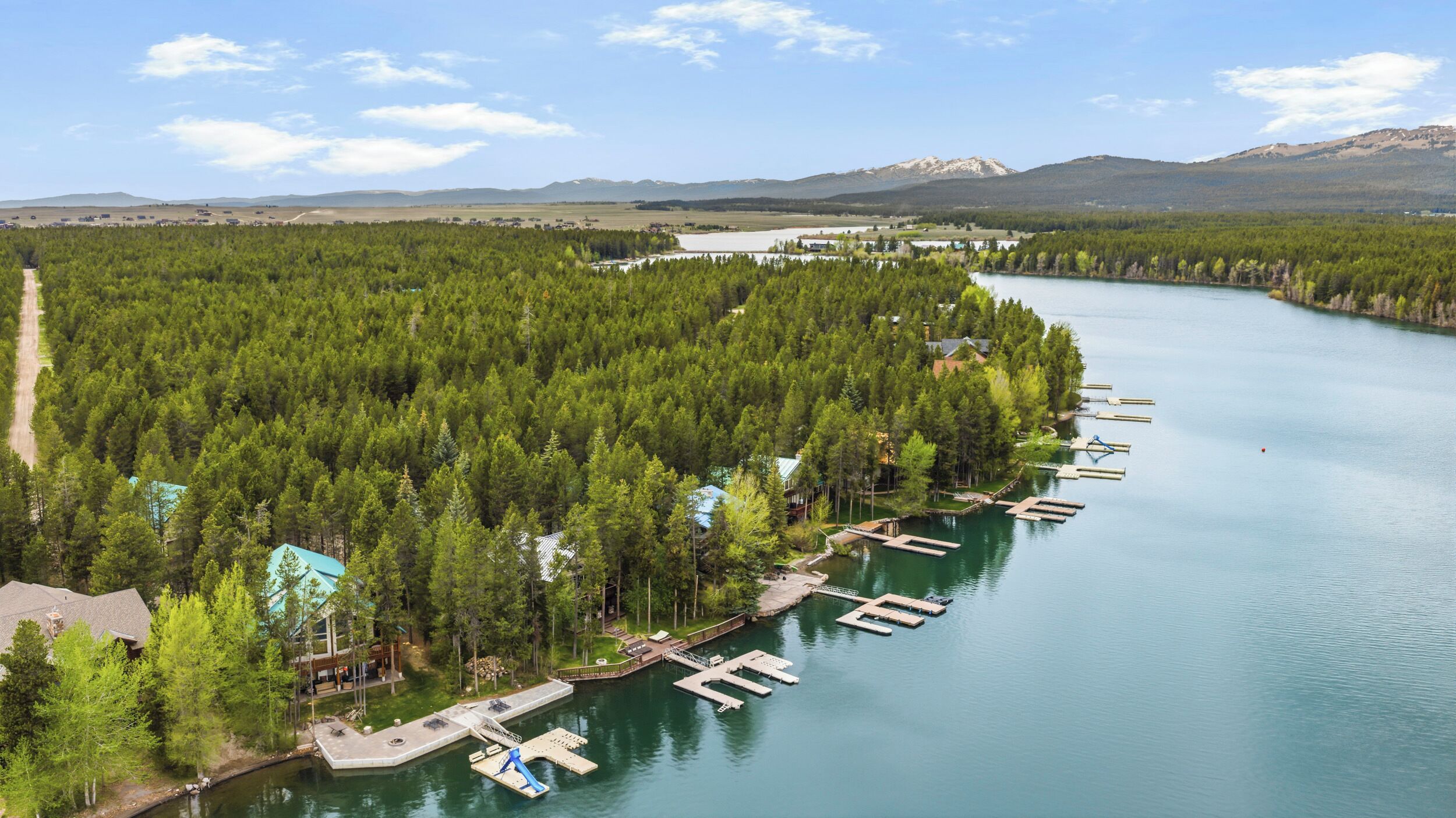 Une propriété située au bord du lac, avec des bateaux amarrés, un petit quai et une zone boisée.