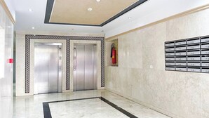 A modern elevator area with two elevators, a fire extinguisher, and mailboxes on the wall.