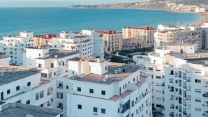 A coastal cityscape with white buildings and a clear view of the sea.