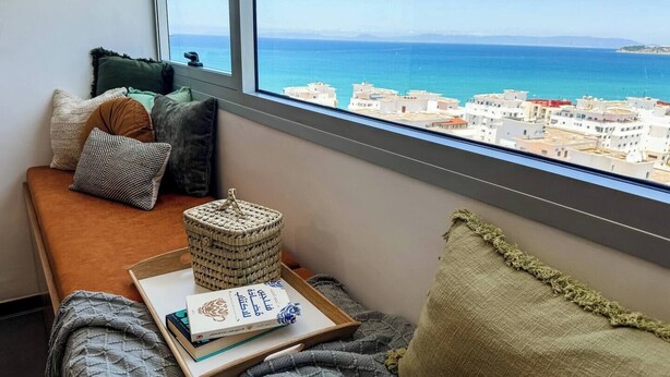 A cozy reading nook with a view of the sea and buildings.